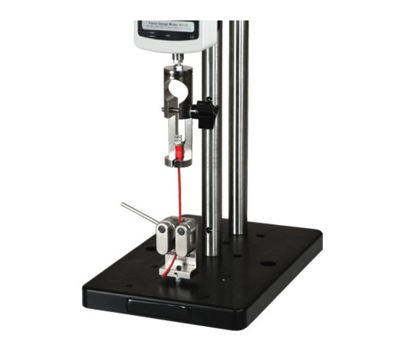 G1001 mostrada en una aplicación típica de prueba de tracción de terminales de cable, utilizada junto con un dinamómetro digital, un banco de pruebas y una empuñadura de doble rodillo G1002.