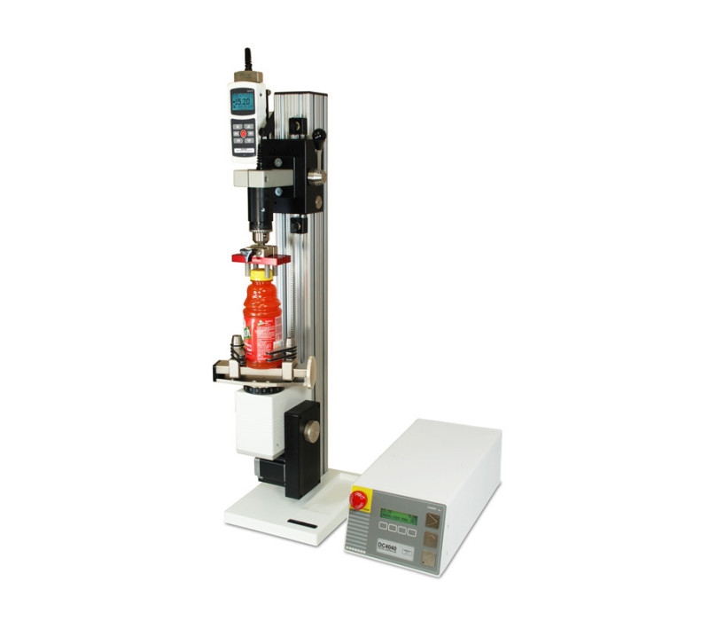 La configuración de prueba de par motorizada CAP-TSTM-DC, mostrada en una aplicación típica de prueba de torsión de tapón de botella con indicador de fuerza/torsión M5I, sensor de torsión de la serie R50, agarres G1023 y G1058.